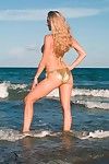 Sexy bodied leggy model Anita Dark in bikini poses on the beach by the sea