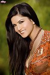 Gorgeous brunette Sunny Leone slides hand under her tunic to show her tits and toy her pussy